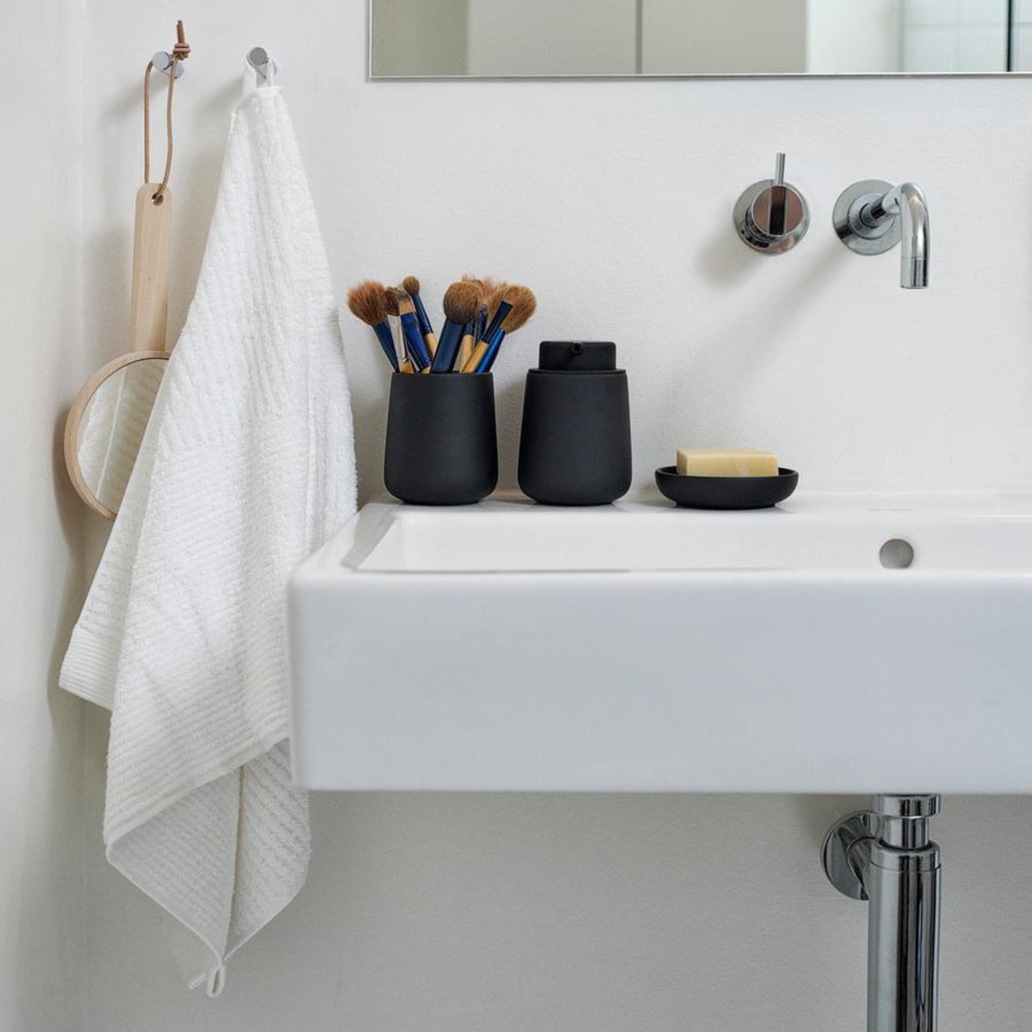 De Zone Denmark Nova One Tandenborstelhouder Zwart brengt moderne stijl naar je badkamer, door zwarte houders voor tandenborstels te combineren met een witte wastafel, ronde spiegel en houten badborstel voor een strakke look.