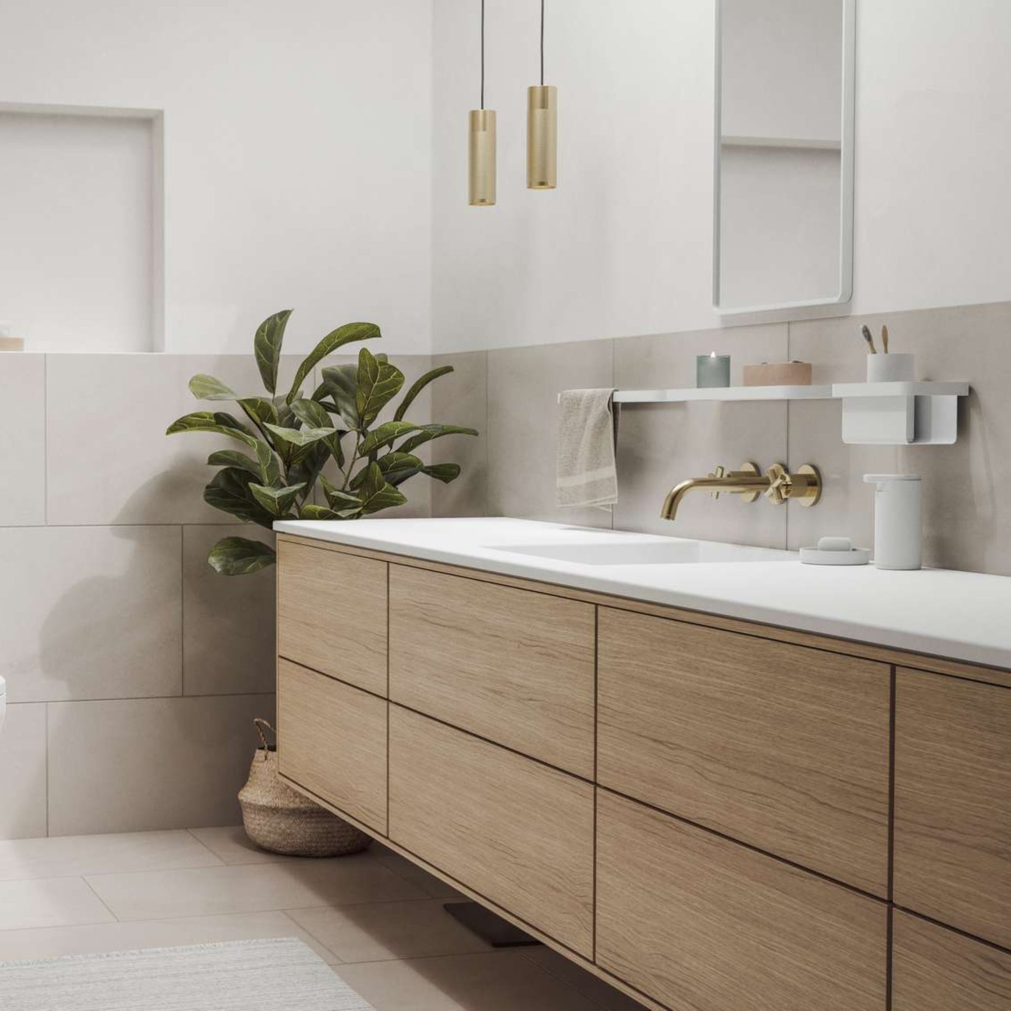 Een moderne badkamer met lichthouten kasten, een wit aanrecht, gouden armaturen, een rechthoekige spiegel, hanglampen en een plant in pot. De Zone Denmark Rim Tandenborstelhouder Wit voegt stijlvolle organisatie toe aan de minimalistische inrichting.