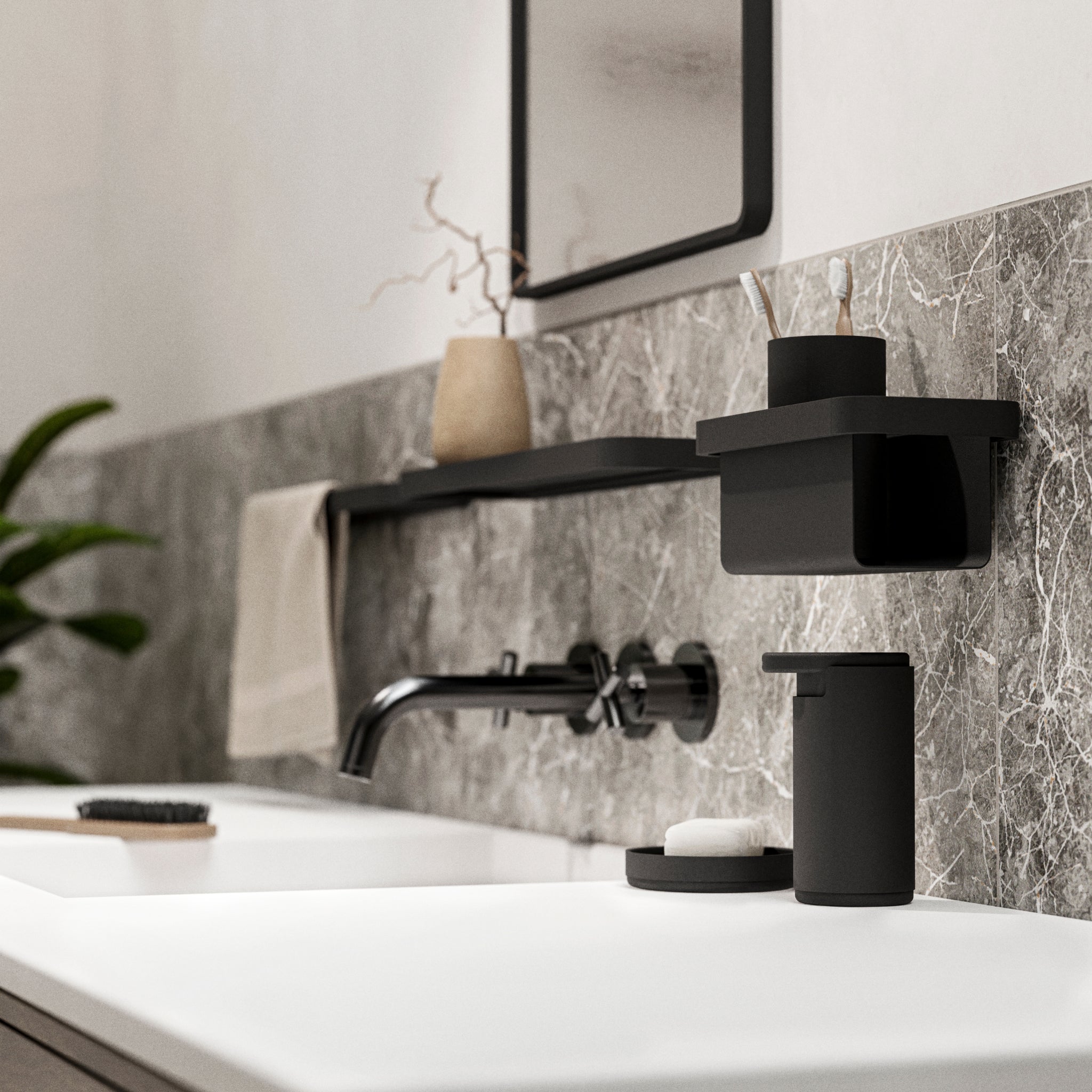 Een moderne wastafelopstelling met een strakke zwarte kraan, zeepdispenser, organizer en de Zone Denmark Rim Tandenborstelhouder Zwart van Zone Denmark op een plank tegen grijs marmer. Een beige handdoek en een plant in pot voegen warmte toe.