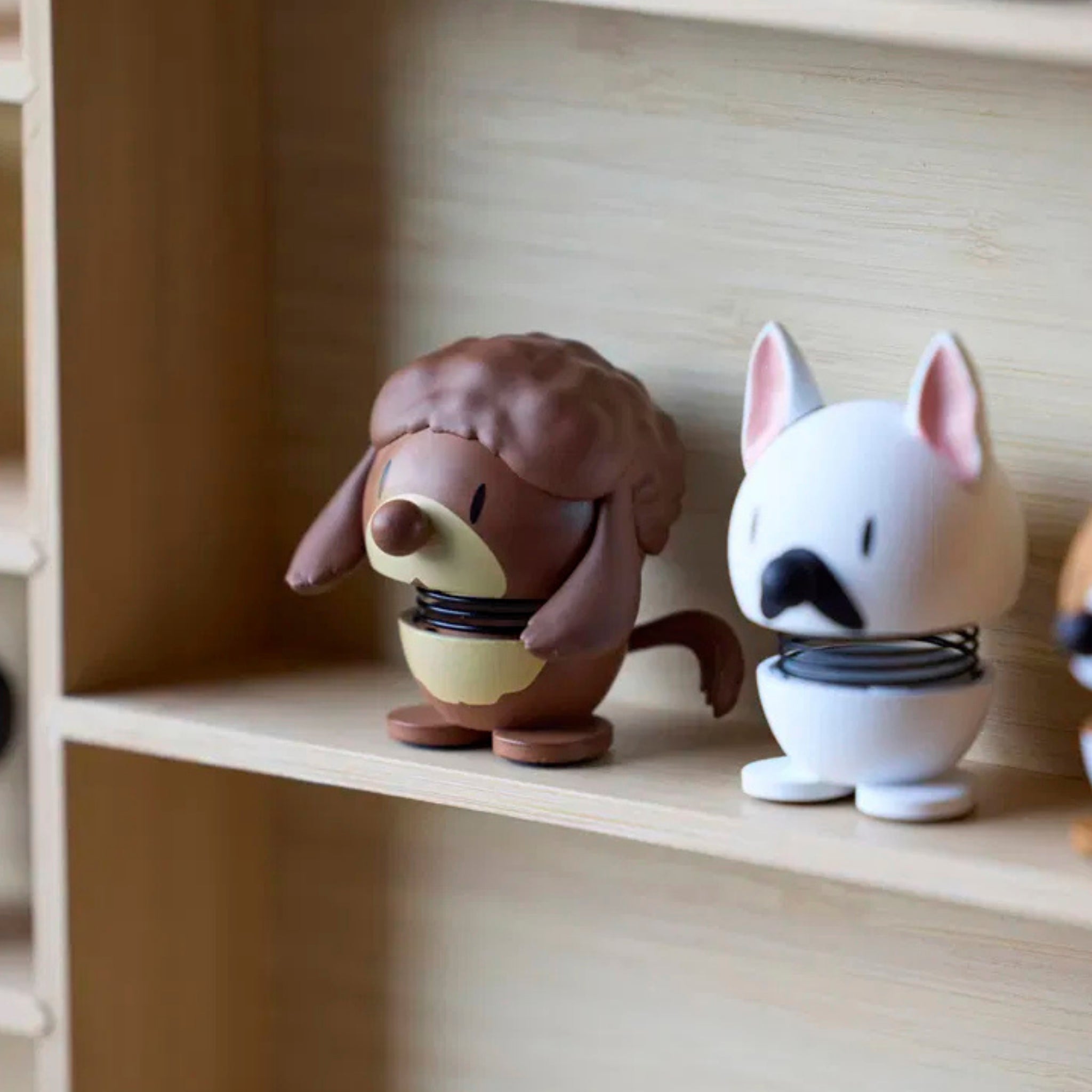 Op een houten plank staan twee kleine dierfiguurtjes met verende lichamen: een bruine egel en de Hoptimist Franse Bulldog Hond Wit/Zwart XS van Hoptimist, een ideaal cadeau voor hondenliefhebbers.