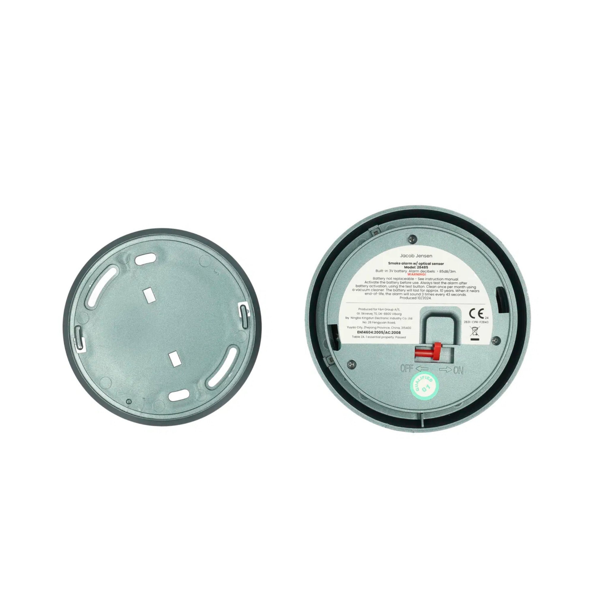 Twee ronde objecten op een witte achtergrond: links zie je een effen deksel met gleufjes, rechts de achterkant van de Hoptimist Jacob Jensen Optical Rookmelder Groen D10, met Scandinavische designelementen zoals een schakelaar, label en batterijvakje.