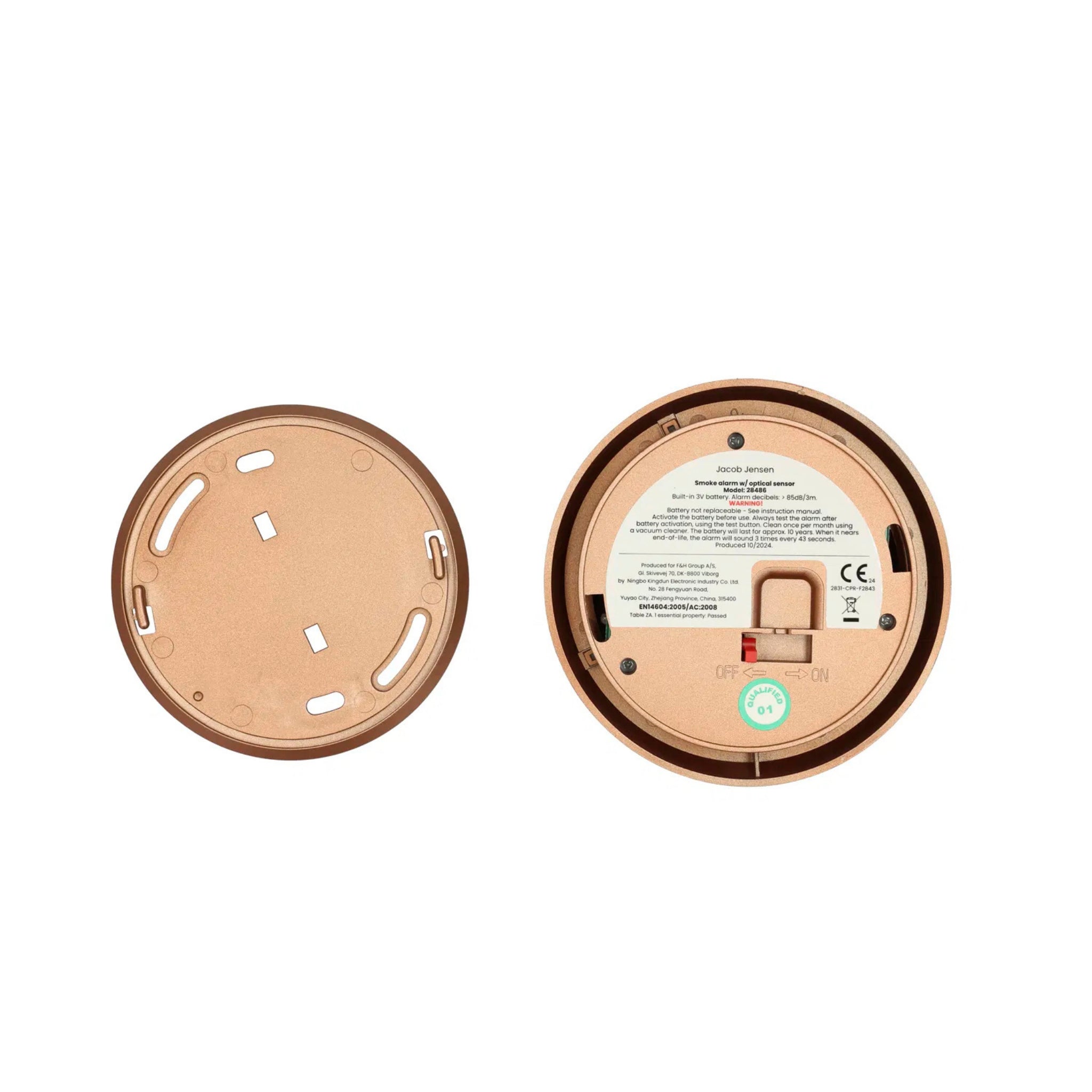 Twee ronde bruine plastic voorwerpen van boven: links een deksel met gleuf; rechts een basis met etiket, schakelaar, batterijvak en symbolen - een afbeelding van de Jacob Jensen Optical Rookmelder Koper D10 rookmelder.