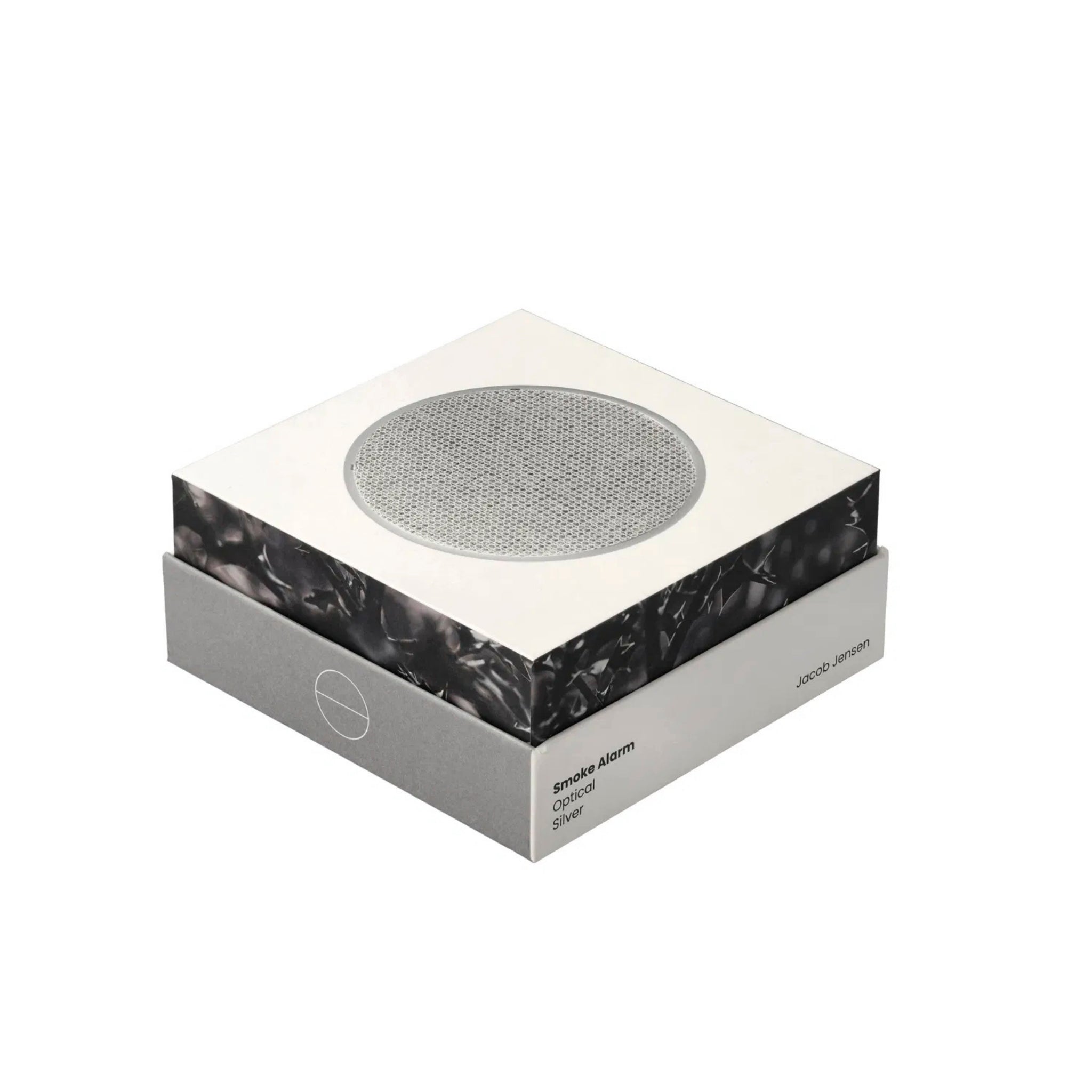 De Jacob Jensen Optical Rookmelder Zilver D10 heeft een Scandinavisch ontwerp, met een vierkante vorm, een slanke witte en grijze verpakking en een ronde sensor van zilvergaas bovenop, tegen een effen witte achtergrond.