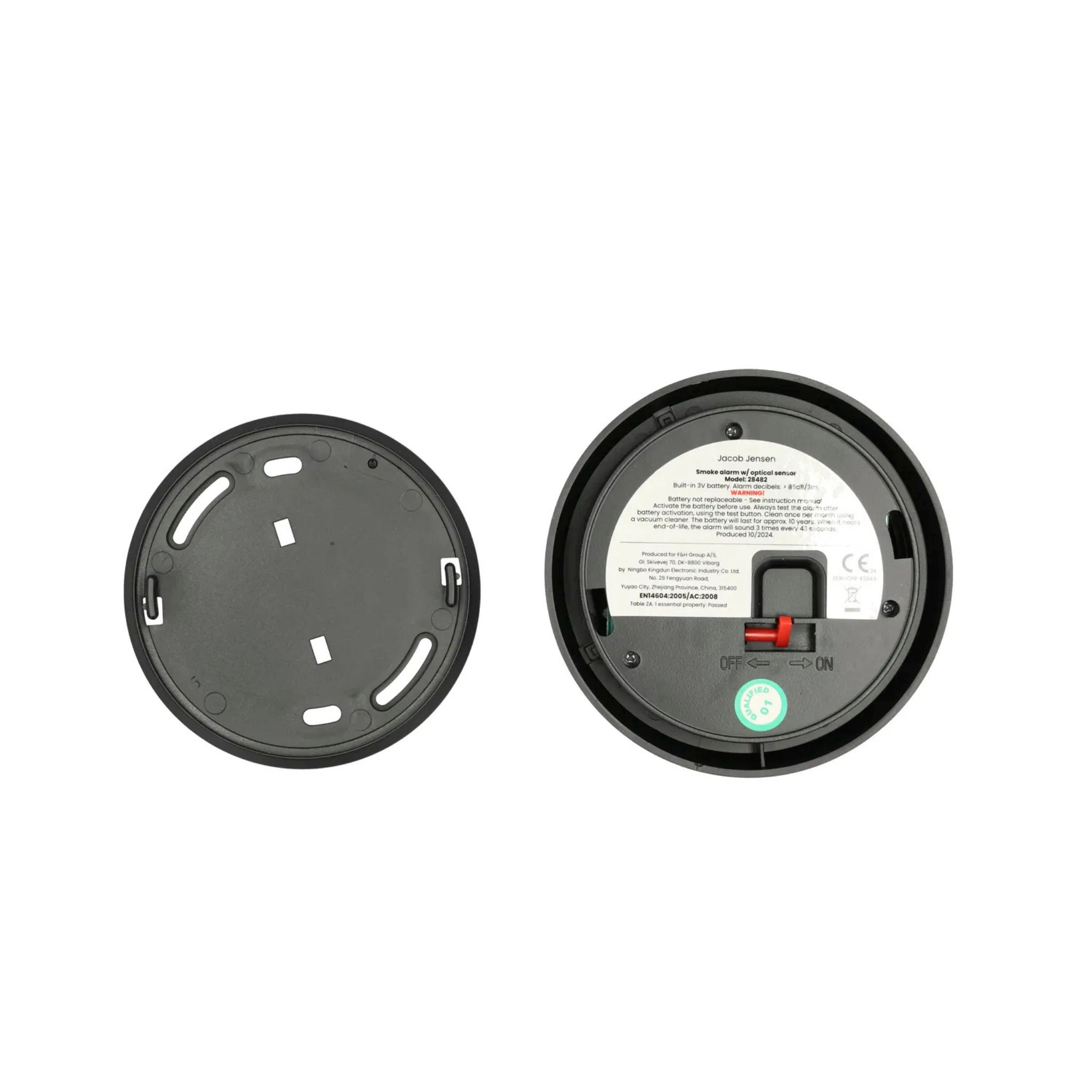 Er zijn twee ronde zwarte plastic objecten te zien: links een gewoon deksel met sleuven en rechts de achterkant van een Jacob Jensen Optical Rookmelder Zwart D10 met een label, rode schakelaar en aan/uit-markering.