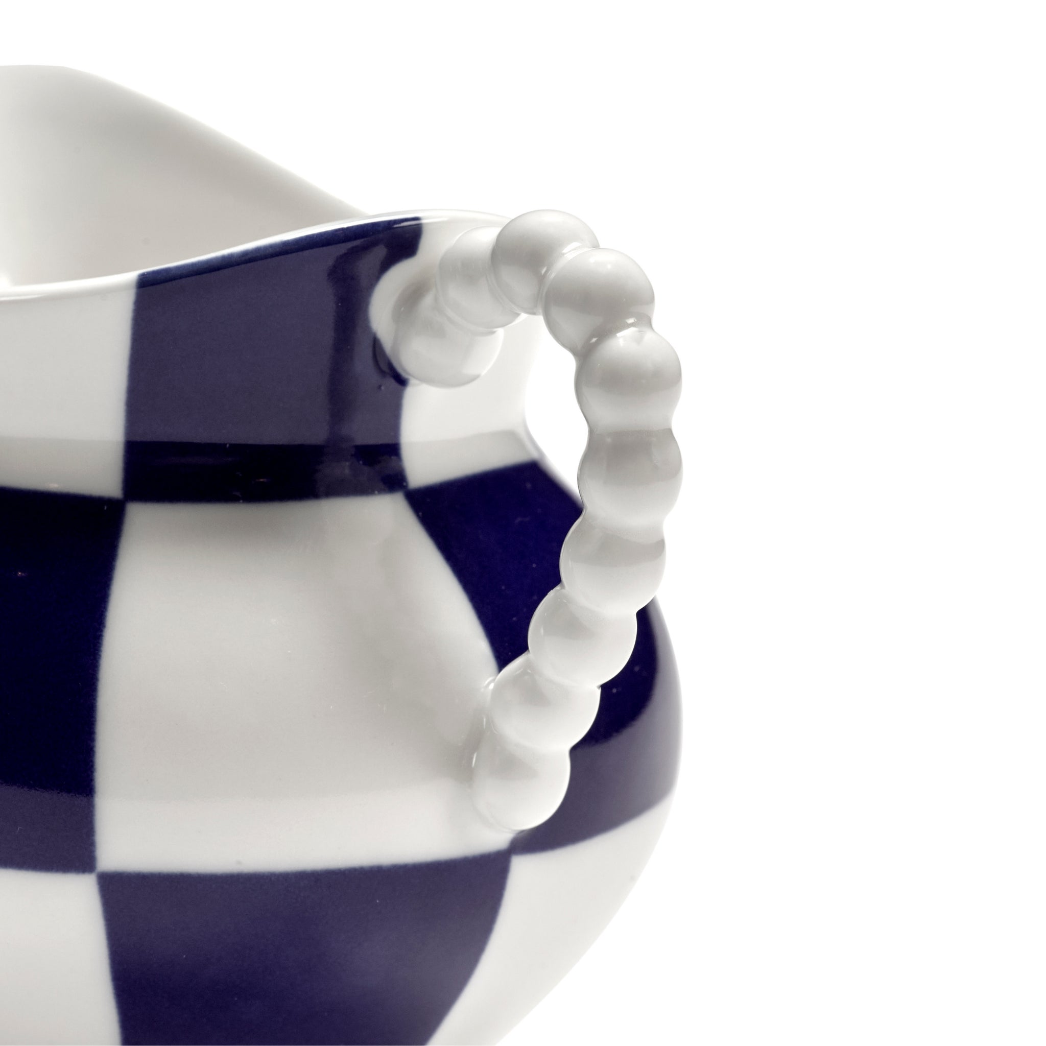 Close-up van het Serax Wouters & Hendrix Fête Des Bêtes Melkkannetje Blauw Wit, met een kralenhandvat en een vet blauw-wit dambordpatroon op een witte achtergrond.