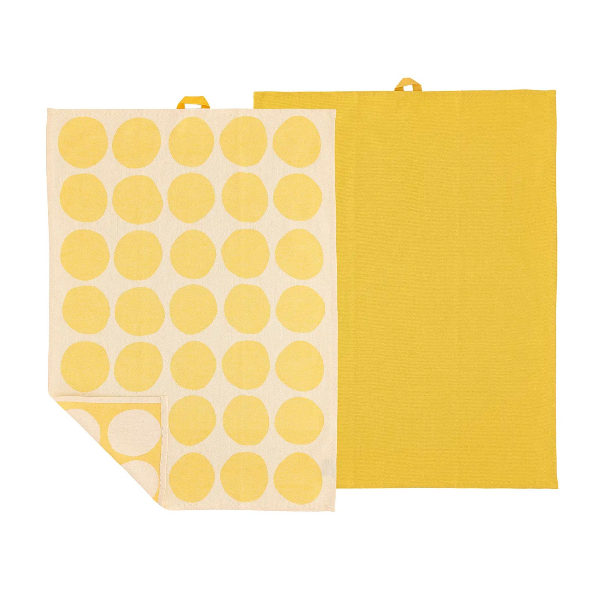 De Södahl Bubbles Theedoek Geel 2 st. set bestaat uit twee theedoeken - een effen gele en een crèmekleurige met opvallende gele stippen, beide met gele ophanglussen voor een vleugje Scandinavische stijl en gemak in je keuken.