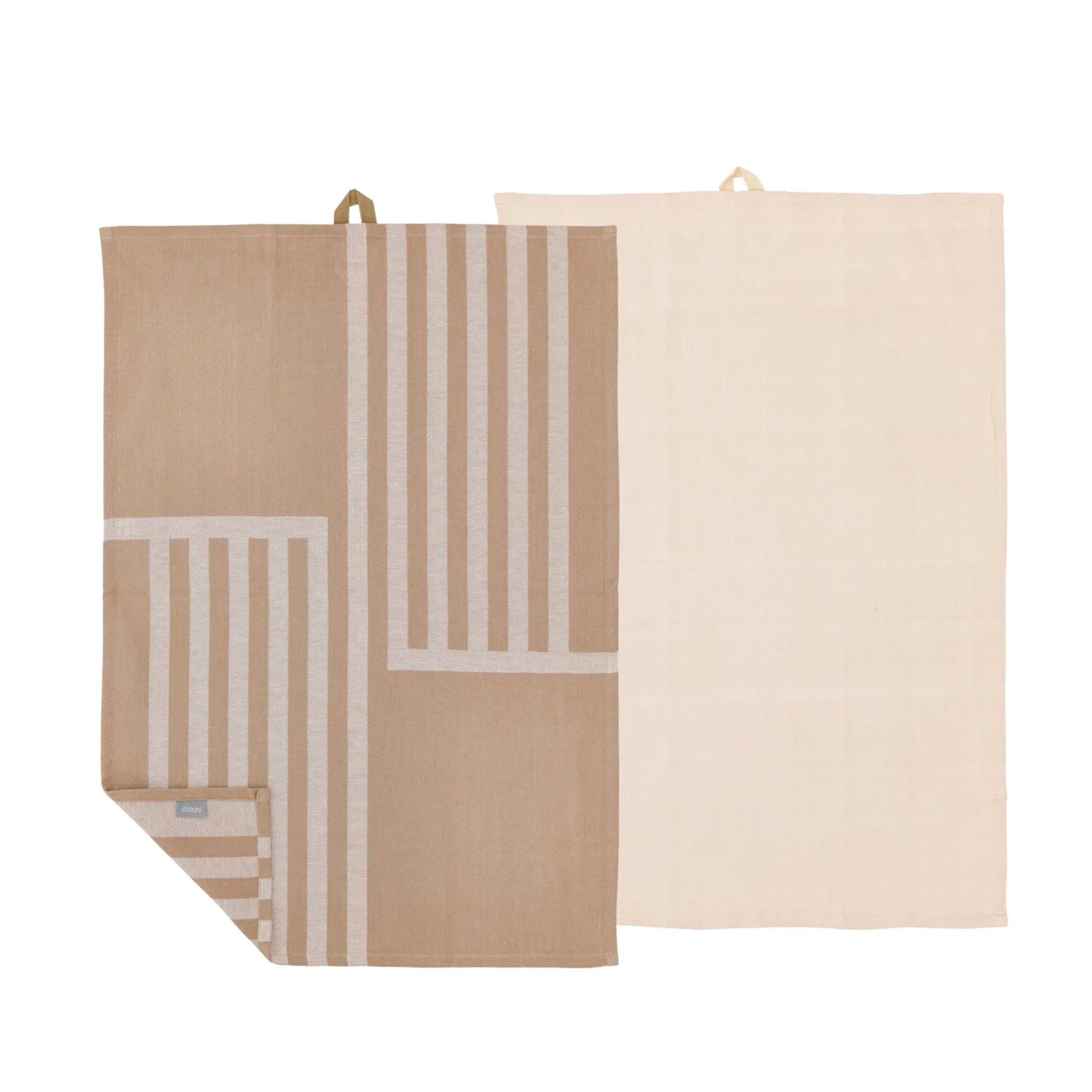 De Södahl Reflection Theedoek Taupe 2 st. set bestaat uit twee rechthoekige keukendoeken: een met een beige en wit gestreept patroon, de andere effen lichtbeige. Beide hebben ophanglussen; de hoek van de handdoek met patroon is omgevouwen zodat de onderkant zichtbaar is.