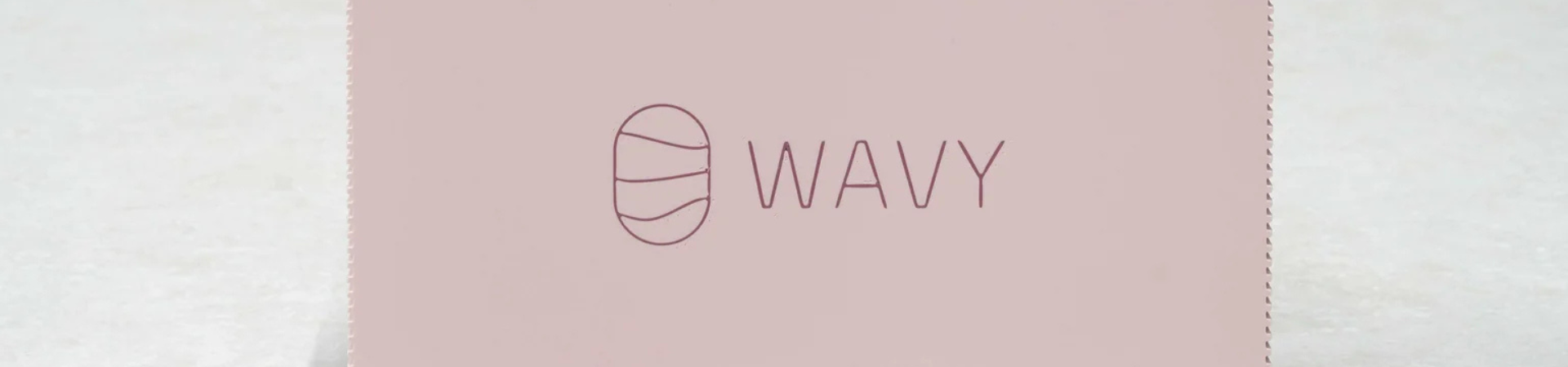 Een lichtroze kaart met een minimalistisch logo van een ovaal met daarin drie golvende lijnen naast de tekst WAVY in dunne hoofdletters.