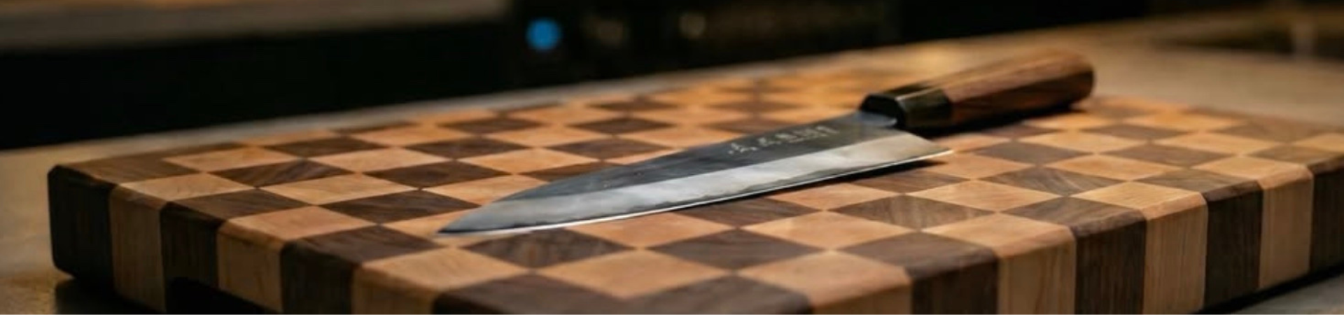 Een scherp koksmes met een houten handvat rust op een geruite houten snijplank, op een aanrecht met een onscherpe achtergrond.