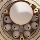 Een bovenaanzicht in een oven toont verschillende handgedraaide, ongeglazuurde vazen en de AB Ceramics Olijfolie Fles Grijs Opaal 84 cl op ovenplanken - ideaal voor het maken van unieke keukenaccessoires van AB Ceramics.