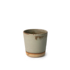 De AB Ceramics Beker Geel Mos 20 cl is een handgedraaide steengoed beker met mat gele mosglazuur en een ongeglazuurde roodbruine basis. Het minimalistische design en de licht taps toelopende vorm geven het keramiek een uniek karakter.