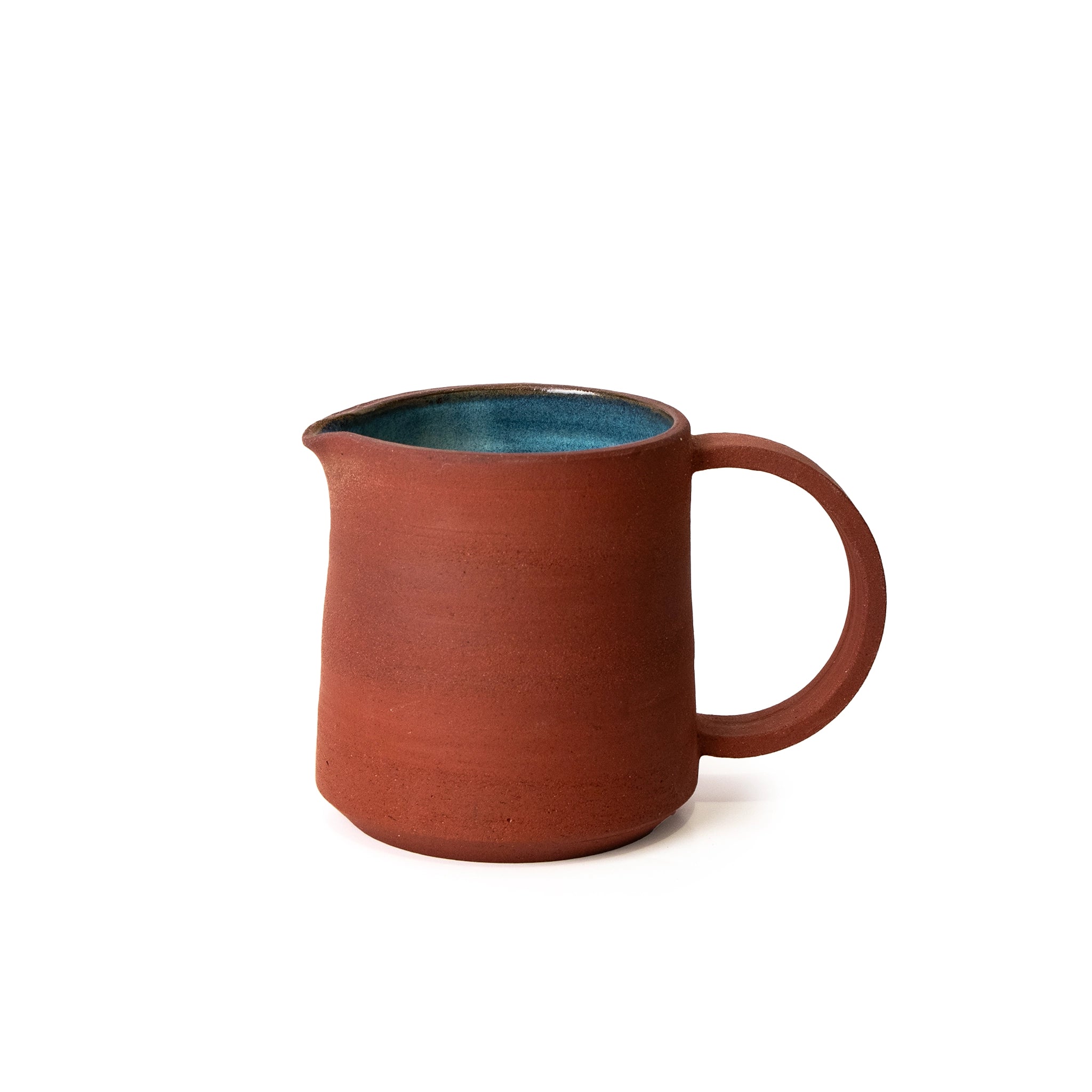 De AB Ceramics Karaf 9 Rood Opaal Blauw 40 cl is een handgegoten kan van rode klei, met een matte roodbruine buitenkant, groot rond handvat en glanzend blauw opaal geglazuurde binnenkant op een witte achtergrond.