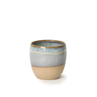 De AB Ceramics Mok Wit Opaal/Blauw is een handgedraaide steengoed mok met ronde vorm, mat beige onderzijde en glanzende wit-blauw-grijze bovenkant. Perfect voor liefhebbers van uniek keramiek.
