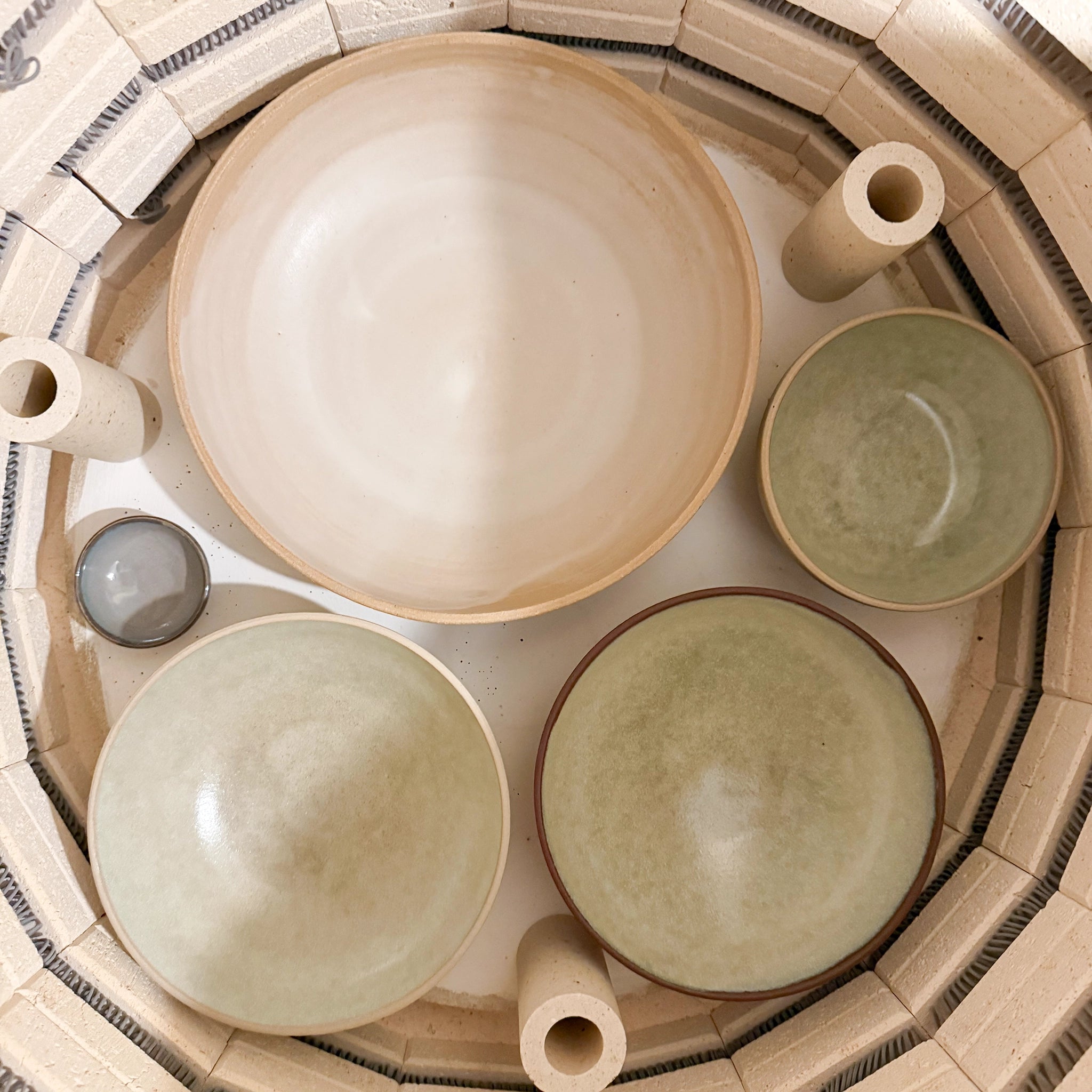 Vier unieke AB Ceramics Noodle Kom Wit Mint D19 kommen - drie mint, één wit - staan opgesteld in een ronde oven. Elk handgemaakt stuk van AB Ceramics varieert in grootte en is ideaal voor noedels of het serveren van je favoriete gerechten.