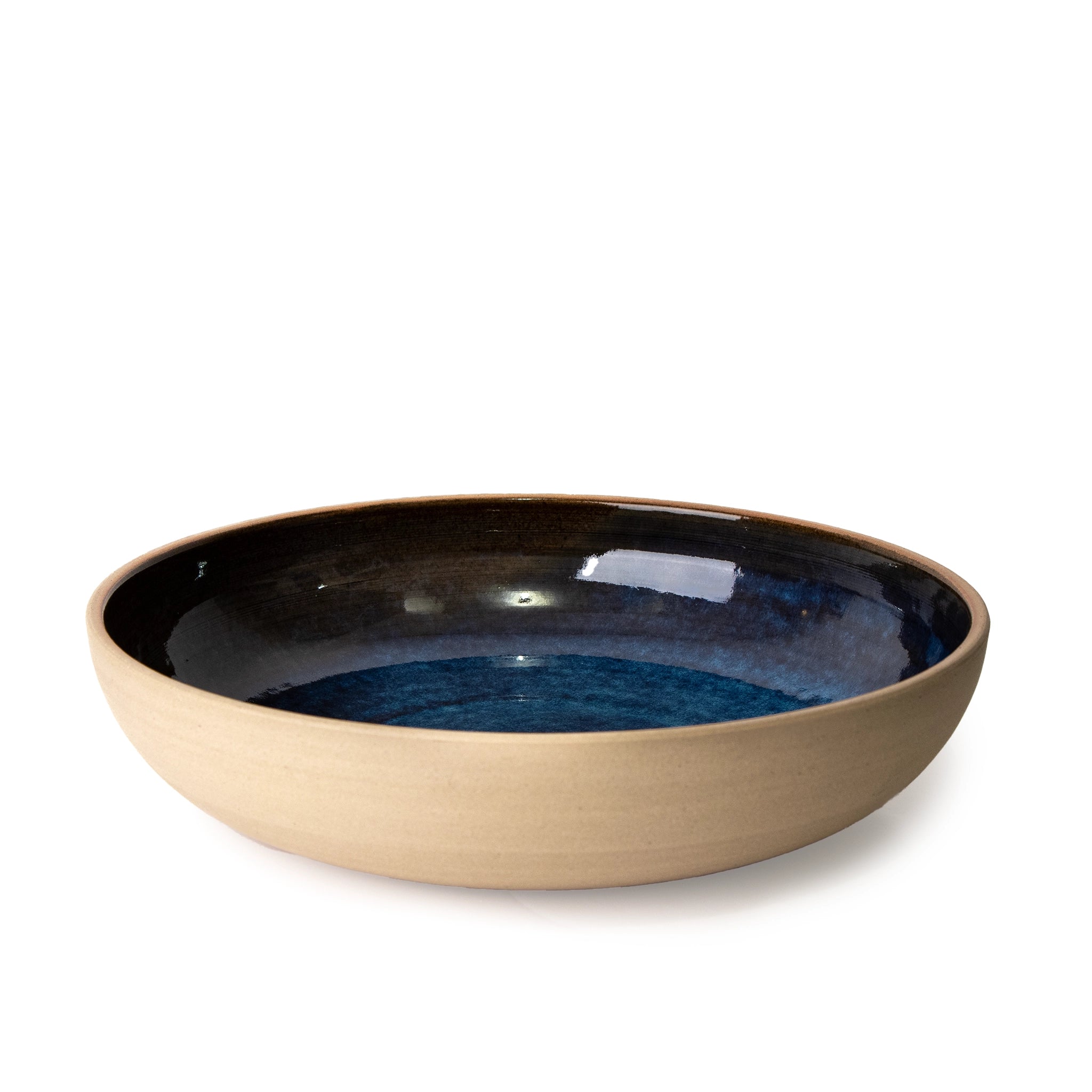 De AB Ceramics Serveerschaal Geel Blauw D25 is een handgemaakte, ondiepe ronde schaal van gele steengoed klei met mat beige buitenkant en glanzend donkerblauw interieur, van het merk AB Ceramics, gefotografeerd tegen een witte achtergrond.