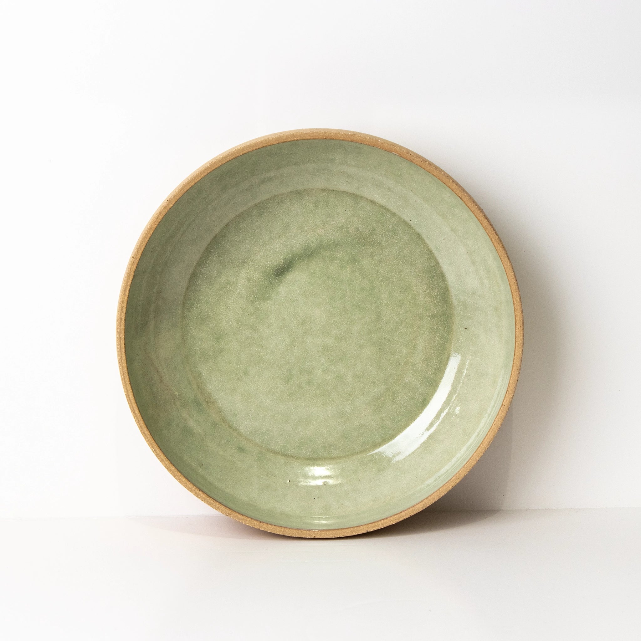 De AB Ceramics Serveerschaal Ruw Mint D24 is een ronde steengoed schaal met een lichtgroen geglazuurd midden en een ongeglazuurde beige rand, tegen een effen witte achtergrond.