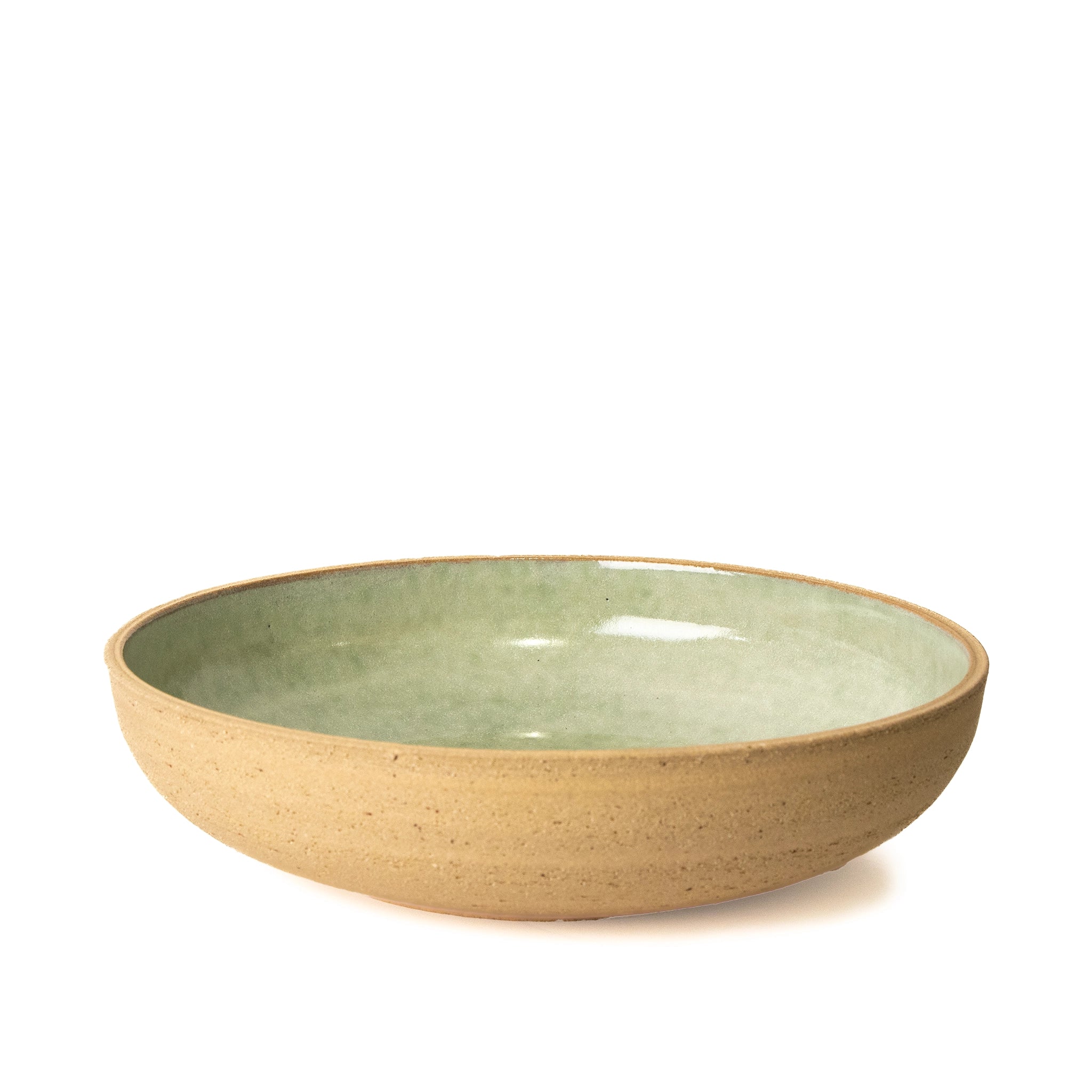 De AB Ceramics Serveerschaal Ruw Mint D27,5 is een ondiepe, ronde steengoed schaal met een getextureerde bruine buitenkant en een gladde mintkleurige glazuur binnenkant, weergegeven tegen een witte achtergrond.