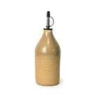 De AB Ceramics Olijfolie Fles Ruw Transparant 60 cl heeft een handgegoten beige keramiek behuizing, glanzende afwerking en metalen schenktuit, waardoor het ideaal is voor het schenken van olie of azijn op je aanrecht.