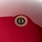 Close-up van het zwarte aan/uit-symbool op het glanzende kersenrood oppervlak van de Addison Ross Bobbin Lamp LED Oplaadbaar, met reflecties zichtbaar rond de knop.