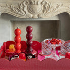 Een decoratief dienblad met glazen potten met snoepjes, een Addison Ross Bobbin zout-en pepermolen rood 24 cm en een glazen standaard met kleurrijke snoepjes voor een sierlijke stenen schouw.