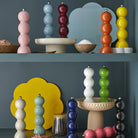 De Addison Ross Bobbin Zout-en Pepermolen Racing Groen 24 cm staat mooi op blauwe planken, omringd door zoutkommen, kleine bordjes en gele en lichtblauwe wolkvormige borden voor een levendige, moderne keukenlook.