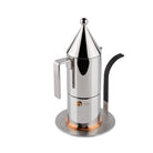 De Alessi Little Helper Inductie Adapter van Alessi is een modern roestvrijstalen accessoire met een hoog conisch deksel, cilindrisch lichaam, hoekige handgreep en basis met koperen accenten, ontworpen voor mokkapotten of espressomachines op inductiekookplaten.