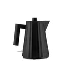 De Alessi Plissé Elektrische Waterkoker Zwart 1 l is een moderne, matzwarte elektrische waterkoker van Alessi, met een geometrisch facetdessin en een groot handvat tegen een effen witte achtergrond.