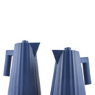Twee blauwe Alessi Plissé Elektrische Waterkoker 1 l waterkokers, met verticale ribbels en hoekige tuiten en handgrepen, staan naast elkaar tegen een witte achtergrond.