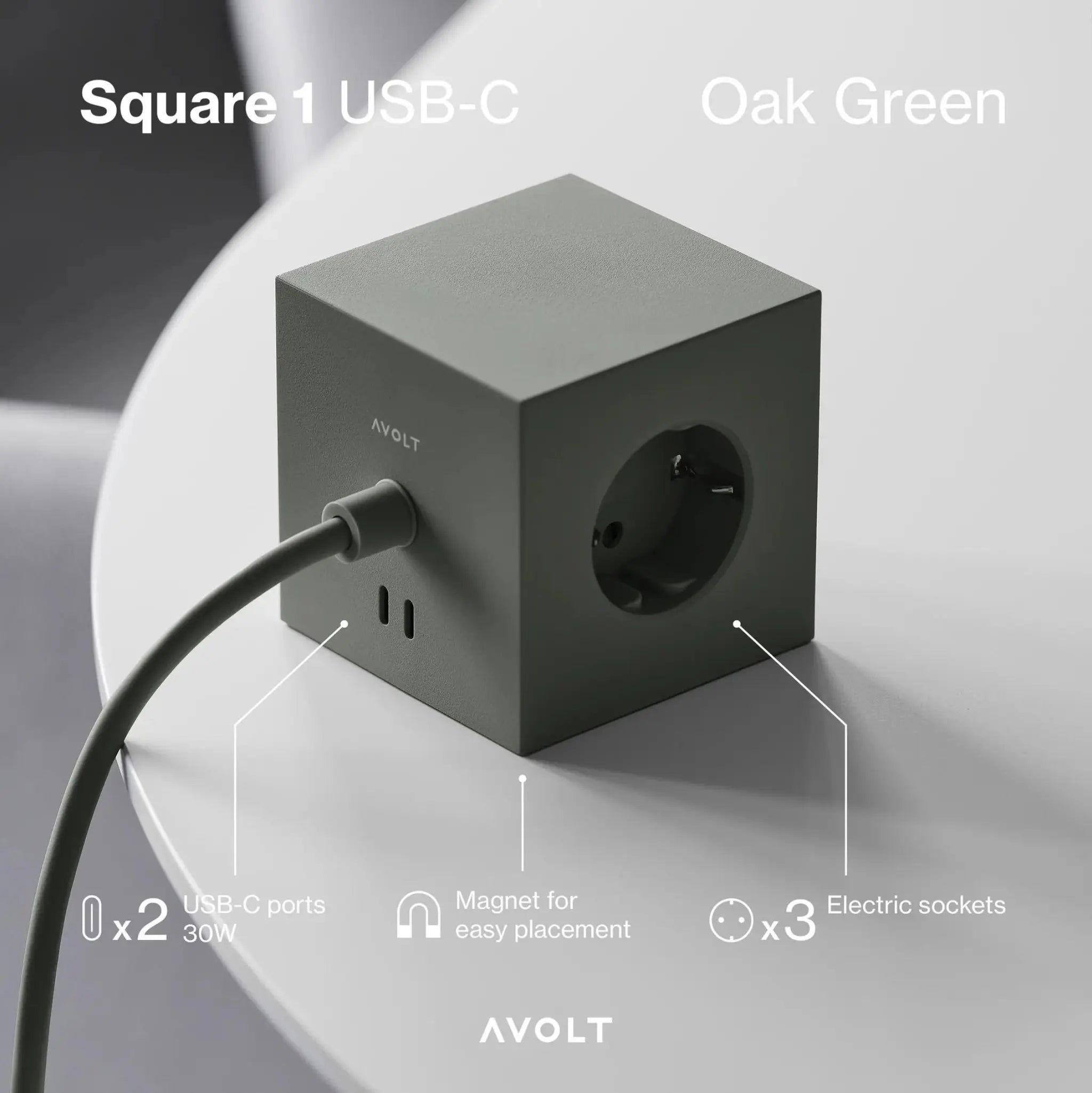 Een Avolt Square 1 USB-C Stekkerdoos Eik Groen 1,8 m ligt op een witte tafel en toont drie stopcontacten met USB, twee USB-C poorten, een powerkabel en een magneet voor plaatsing. Tekst toont de kenmerken en productnaam van Avolt.