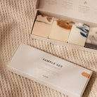 De Azur Sample Set Natuurlijke zepen 4 st. bevat vier plasticvrije, natuurlijke bodybars in verschillende kleuren en patronen. De doos toont de merknaam Azur en is gefotografeerd op beige stof met structuur.