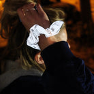 Een persoon met blond haar, gedeeltelijk verborgen, showt de reflecterende Caro Antwerp Caro The Scrunch Club Scrunchie 2 st. - een perfect fiet accessoire - tegen een warm verlichte, onscherpe achtergrond.