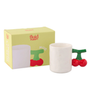 De Fluid Market Mok Kers is een witte keramische mok met een handvat in de vorm van twee rode kersen en een groen staal. De speelse mok wordt geleverd in een gele doos met Fluid Market logo en een afbeelding van de kersenmok.