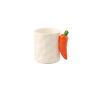 De Fluid Market Mok Wortel van Fluid Market is een witte mok van keramiek met een gestructureerd oppervlak en een 3D oranje wortelhandvat met een groene bovenkant - een origineel cadeau, afgebeeld tegen een effen witte achtergrond.