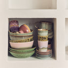 De HK Living 70s Ceramics Koffiekop Bramble toont pastelkleurige en aardse tinten met handgemaakt structuurglazuur, netjes gestapeld op een witte wandplank voor een levendige, ambachtelijke touch.