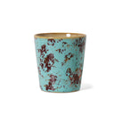 De HK Living 70s Ceramics Koffiekop Patina beker heeft een licht taps toelopende vorm van keramiek met een turquoise glazuur en bruin en roodachtig gevlekte vlekken, die de retrostijl uitstralen, afgebeeld tegen een effen witte achtergrond.