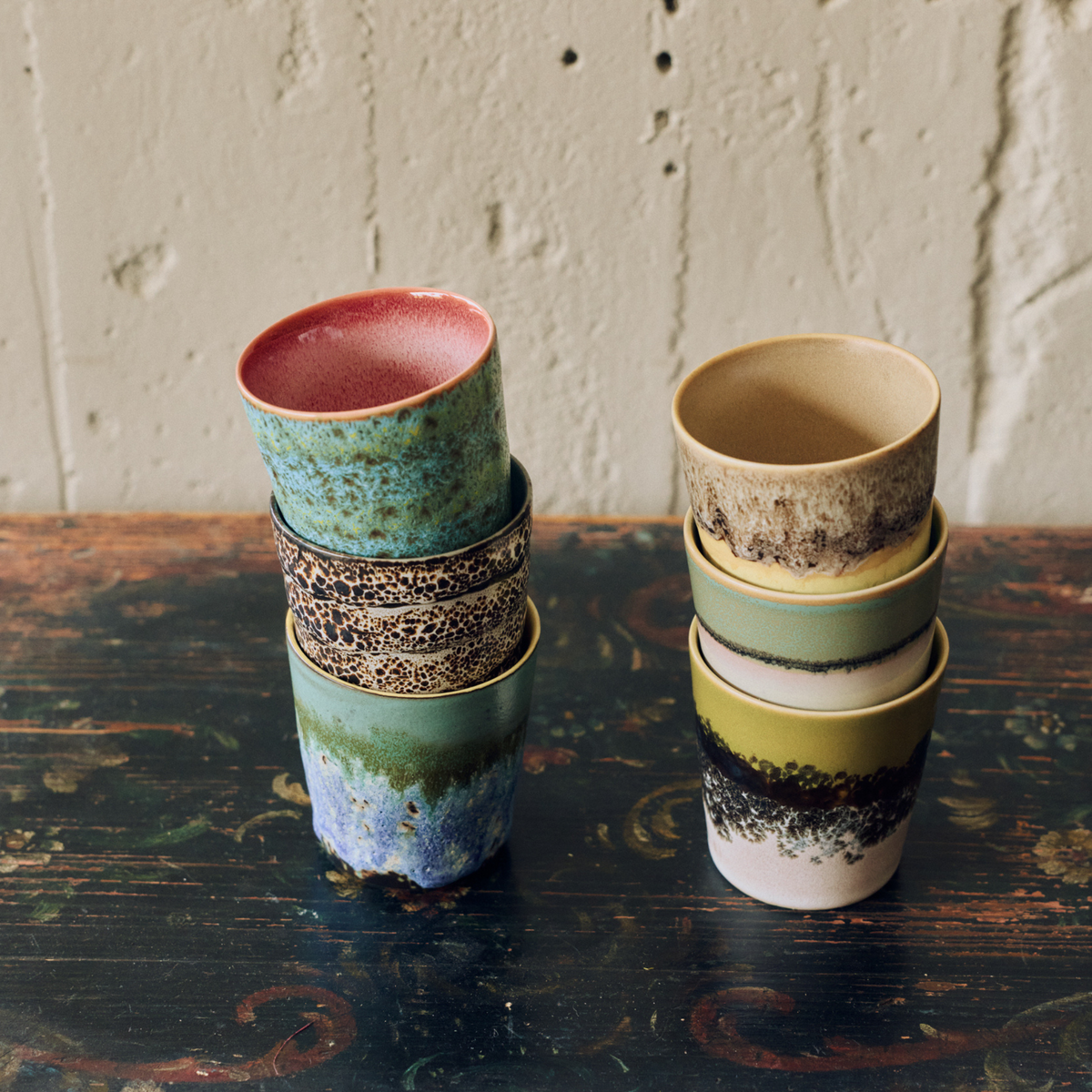 Twee stapels HK Living 70s Ceramics Koffiekoppen op een donkere houten tafel, met Zingy, Brew, Agave, Custard, Gelato en Truffle
