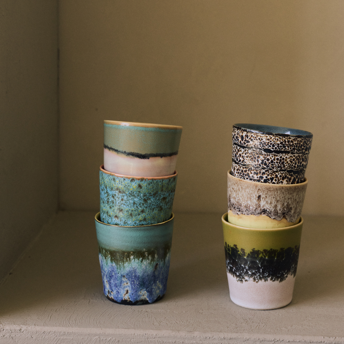 Twee stapels HK Living 70s Ceramics Koffiekoppen in een lichte nis, met Gelato, Zingy, Agave, Brew, Custard en Truffle