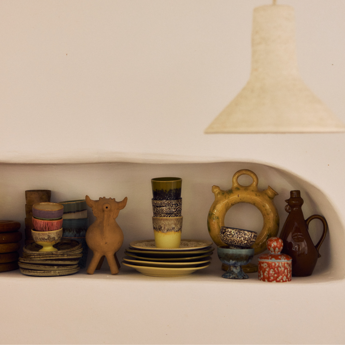 Wandnis met keramiek en een stapel HK Living 70s Ceramics Koffiekoppen Truffle, Custard en Brew