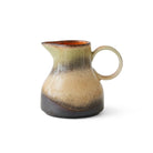 Het HK Living 70s Ceramics Melkkannetje 8AM heeft een ronde handgreep, een smalle tuit en verlopend glazuur in groen, beige en bruin, wat doet denken aan de retro jaren 70 stijl. Afgebeeld tegen een effen witte achtergrond. Merk: HK Living.