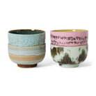 Vier HK Living 70s Ceramics Noodle Kom Dada D13 kommen zijn per twee gestapeld: de linkerset in blauw en bruin, de rechterset met een groene kom met aardse patronen en een roze kom met donkere spikkels - perfecte handgemaakte kommen.