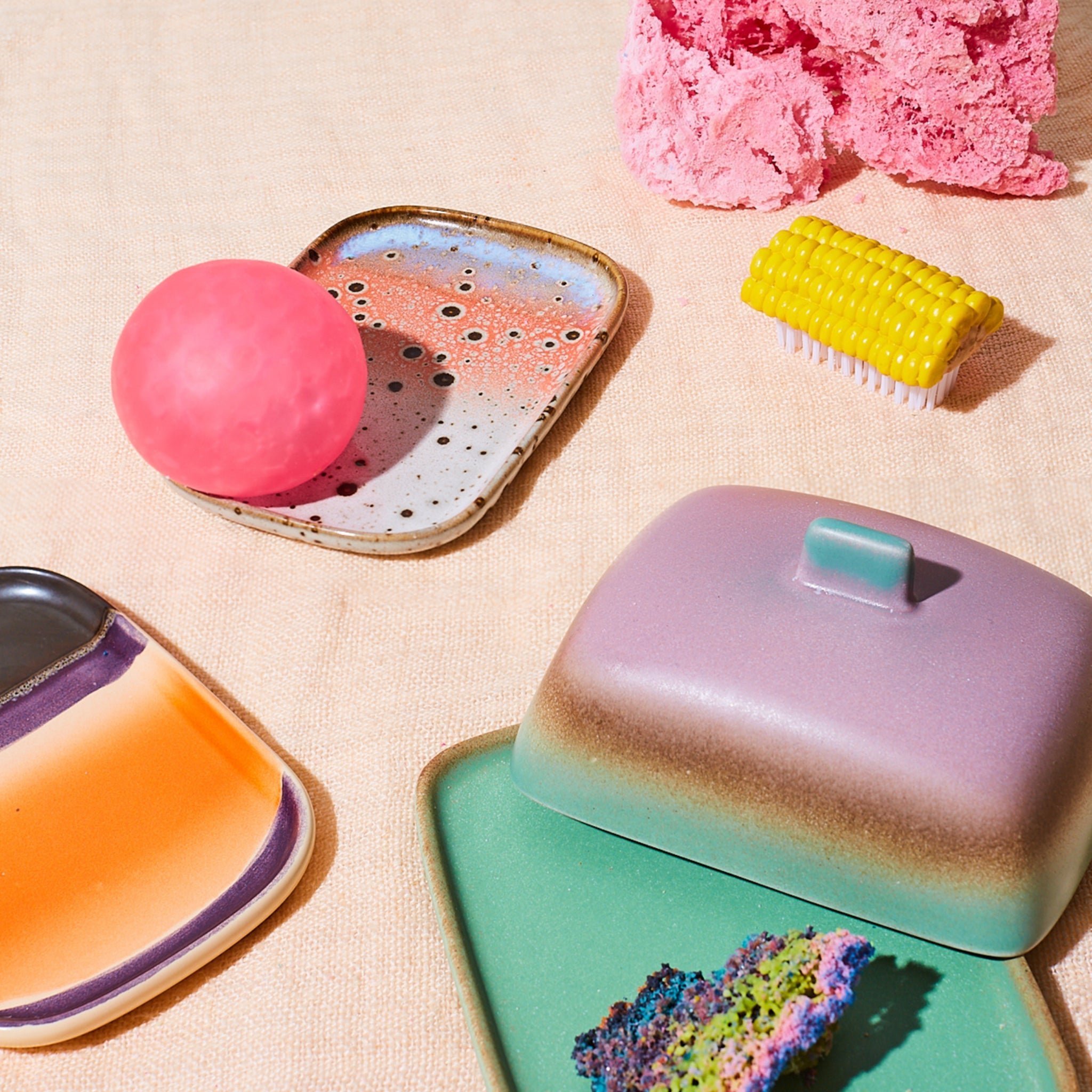 HK Living 70s Ceramics Schaaltje Atlas 2 st. van HK Living is gestyled op lichte stof, gecombineerd met een roze ronde zeep, spons met structuur, gele schrobborstel, kleine schaaltjes en een bedekt botervlootje onder heldere verlichting voor een retro touch.