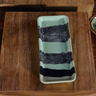 Het HK Living 70s Ceramics Serveerschaaltje River is een rechthoekige groene keramiekschaal met drie zwarte banden-ideaal om retro stijl op tafel te brengen.