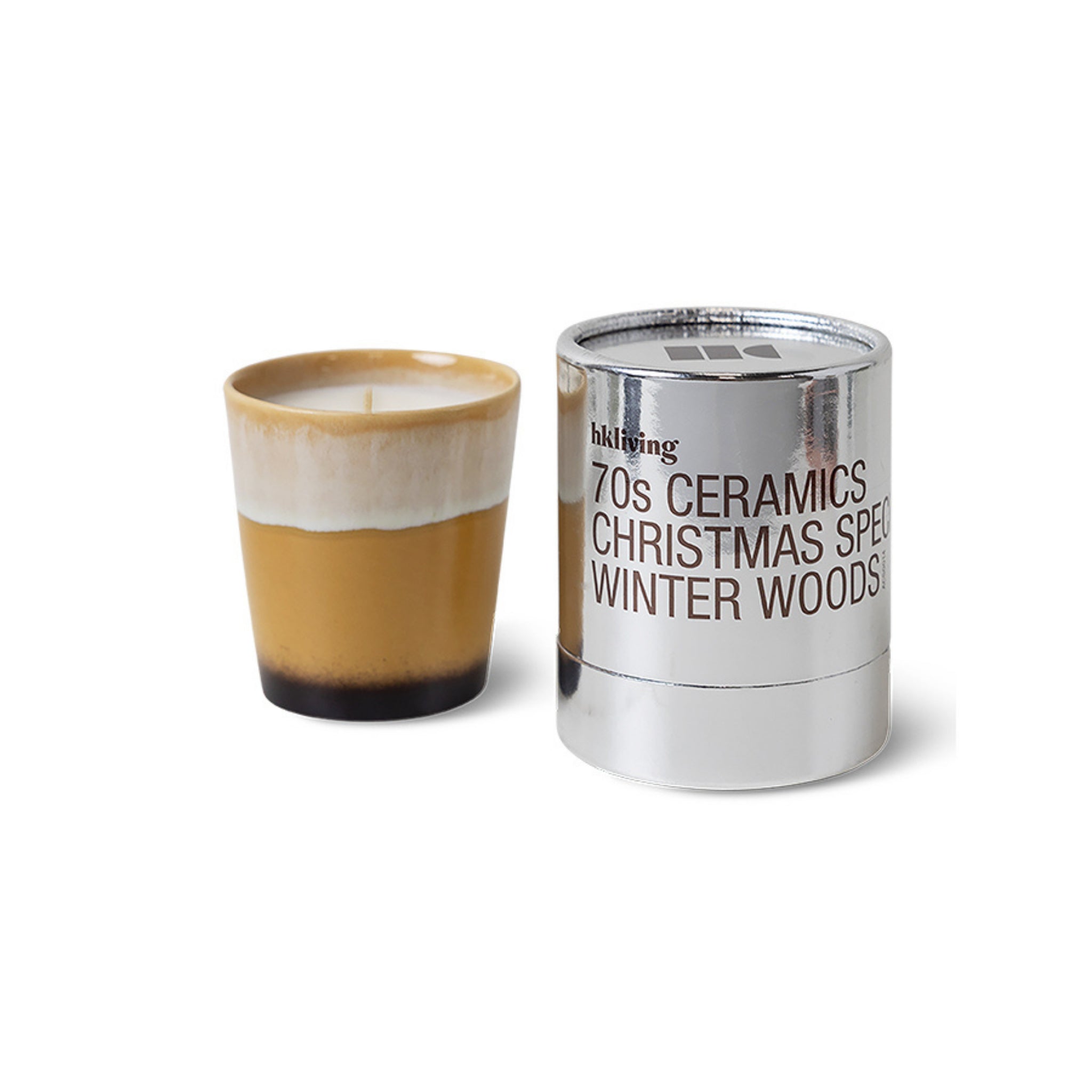 Een kaars van geel en crème keramiek staat naast een glanzend zilveren HK Living Christmas Special Geurkaars Winter Woods houder.