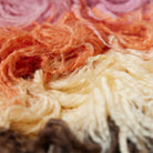 Close-up van kleurrijke garenslierten in roze, oranje, crème en bruin, gerangschikt in golven - perfect om warmte toe te voegen aan je ruimte met de HK Living Fluffy Tapijt Downtown 180/120 van HK Living.