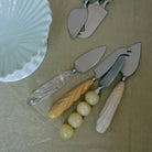 Vier vintage taartscheppen met decoratieve handgrepen rusten op een licht tafelkleed naast een witte keramische schaal met geschulpte rand - een perfecte aanvulling op uw HK Living Kaasmesjes Crème 3 st. set.