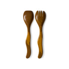 De HK Living Saladebestek Oker 2 st. set bestaat uit een lepel en vork met golvende handvatten, elegant naast elkaar geplaatst op een witte achtergrond-een stijlvol cadeau van HK Living.