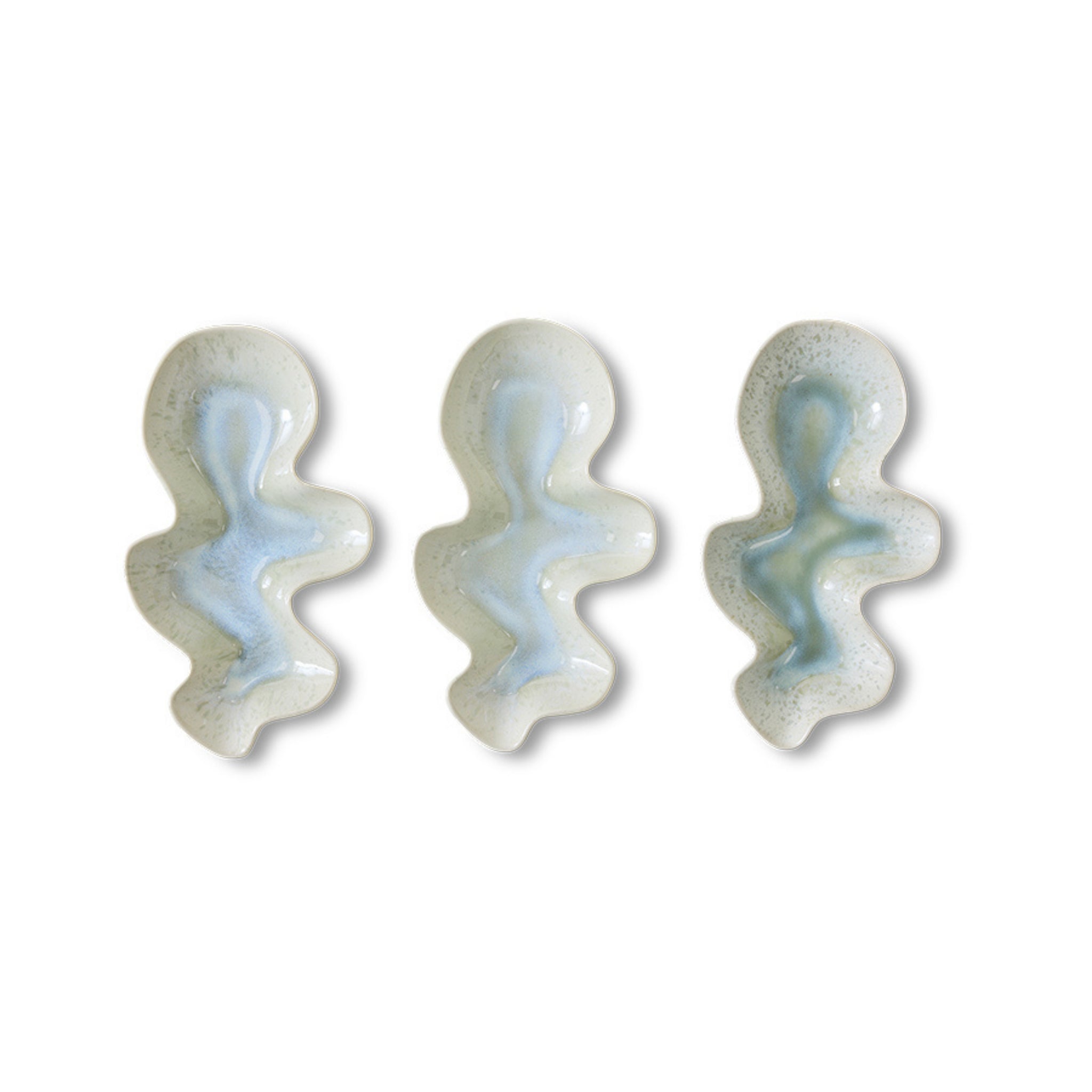 Drie abstracte, golvende keramische figuren met een glanzend wit en lichtblauw glazuur zijn gerangschikt op de HK Living Shell Serveerschaal Oyster, die doet denken aan maritieme tafeldecoratie. Merk: HK Living.