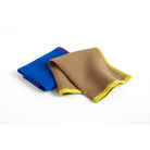 De Hay Canteen Vaatdoeken Blauw Geel 2 st. set van Hay bevat twee absorberende katoenen doeken, ideaal voor het efficiënt schoonmaken van de keuken - een in blauw met paarse bies en een in bruin met gele bies, weergegeven op een wit oppervlak.