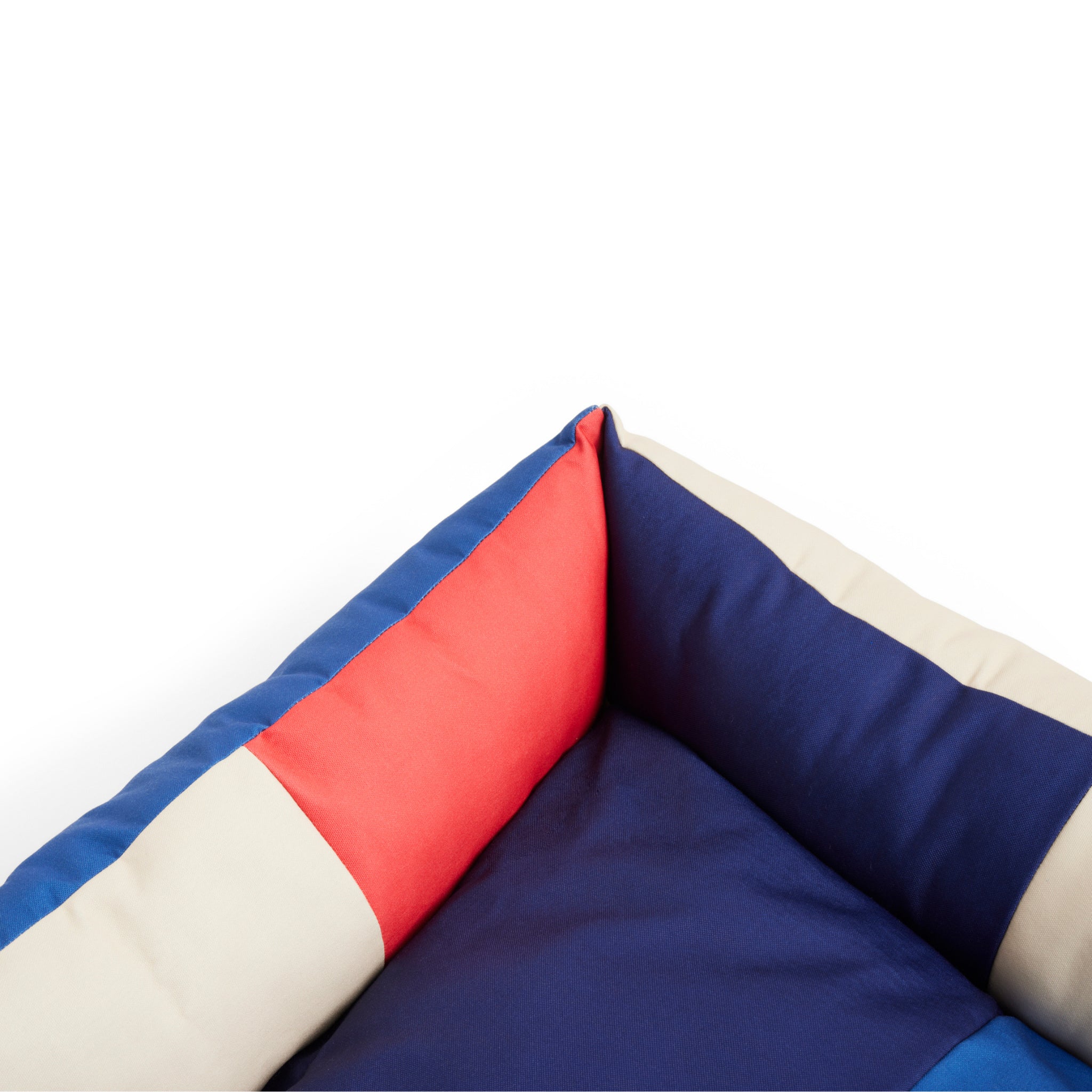 Close-up van de Hay Dogs Hondenmand Rood Blauw 65/78 van Hay, middelgroot met gedempte color-blocked marineblauwe, rode en beige stof. Een stijlvol hondenmand rood blauw accent voor moderne interieurs tegen een effen witte achtergrond.