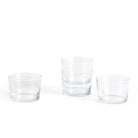 Vier Hay Glas Helder S-kopjes zijn gerangschikt op een wit oppervlak. Met een minimalistisch ontwerp is één paar ruimtebesparend gestapeld, terwijl de andere twee kleine glazen naast elkaar staan.